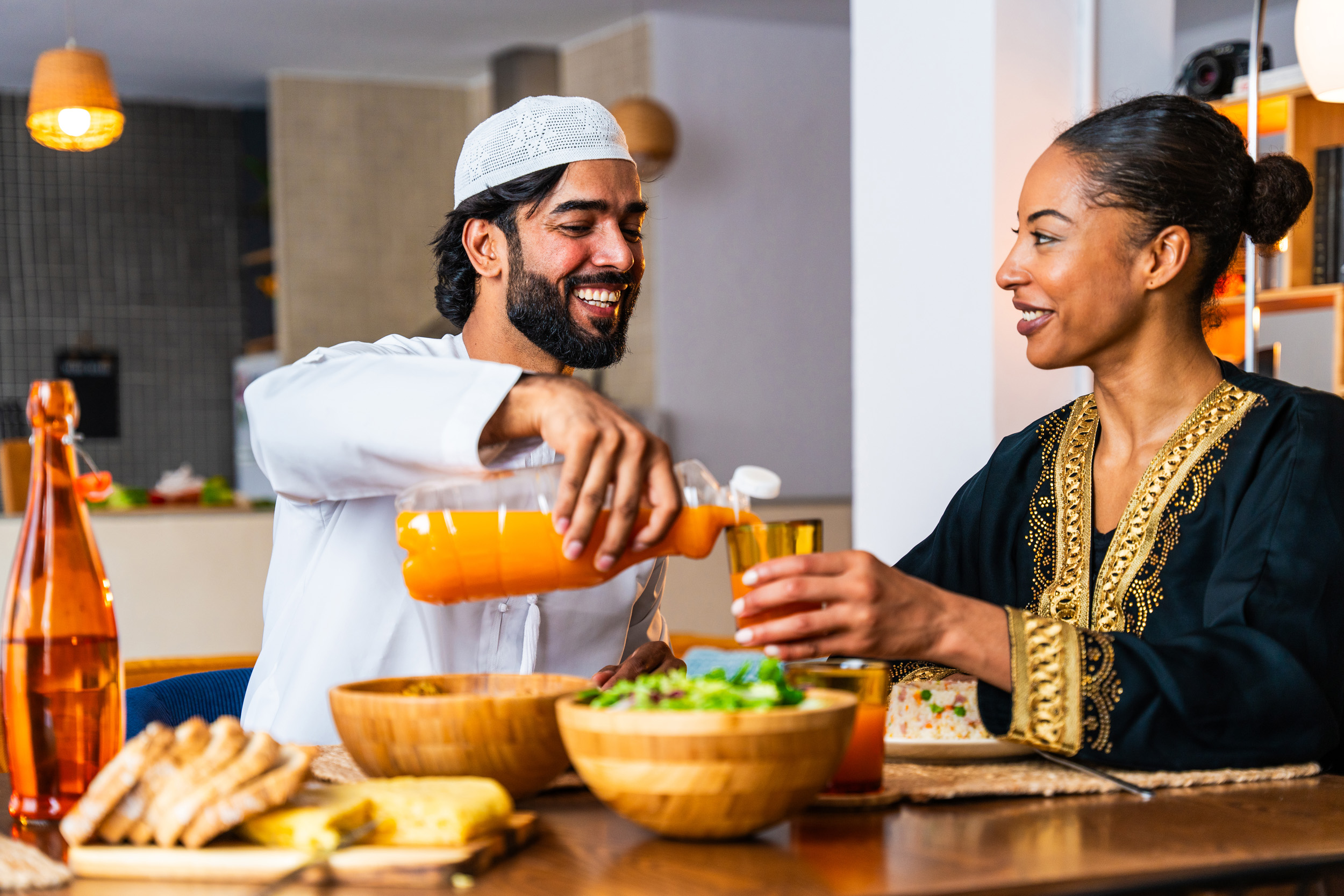 Happy beautiful young Arab couple with emirati clothing having meal