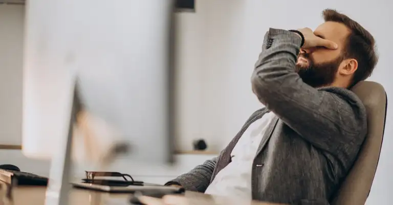 Stressed businessman working at desk showing signs of high-performance burnout and mental fatigue